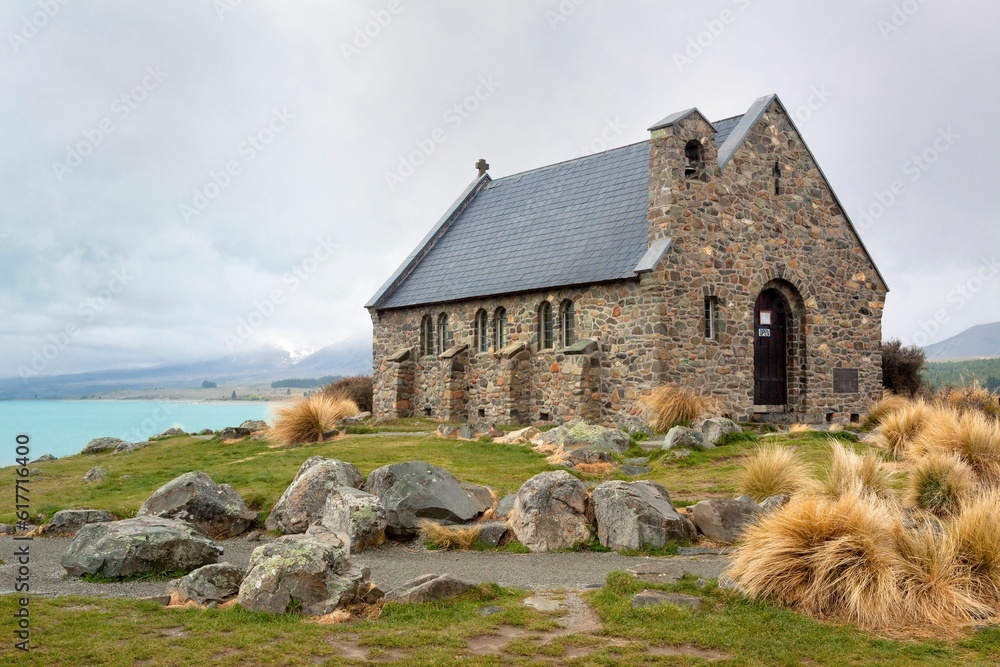 Sticker an old stone church overlooking a lake and a green field