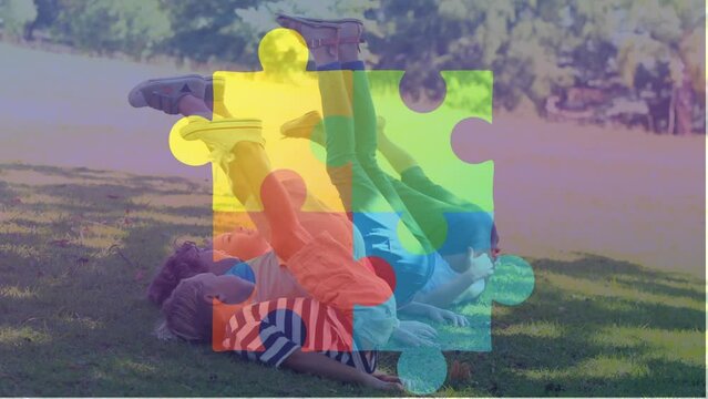 Animation of jigsaw puzzle over diverse children lying on green filed and raising legs towards head