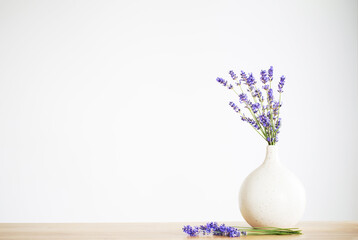 lavender flowers in ceramic vase on gray background