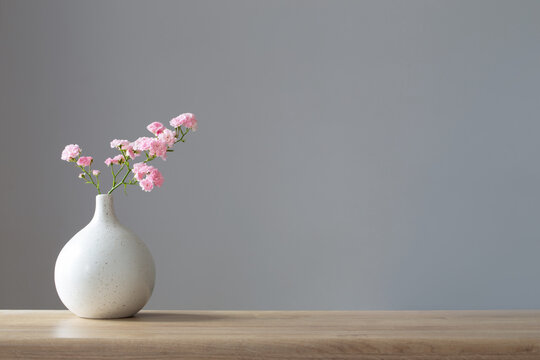 pink roses in ceramic vase on wooden table