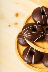 chocolate donuts on a wooden tray. flour donuts with chocolate icing on a wooden plate. colorful pastries for guests