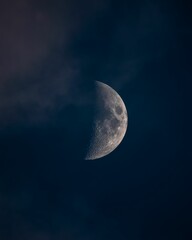 Large half moon partially obscured by clouds in the night sky with a blurred background