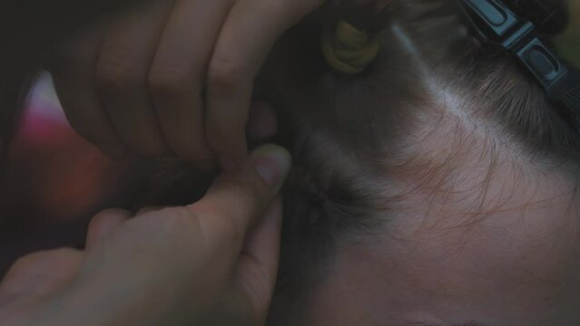 Process of weaving making boxer braids cornrows by a hair braider.