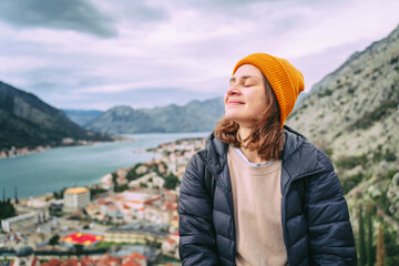 Young woman traveler enjoying the view of the old town of Kotor and the Bay, in Montenegro on an...