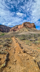 Scenic view on massive mesa cliff The Battleship seen from Bright Angel and Plateau Point hiking trail, South Rim of Grand Canyon National Park, Arizona, USA. Barren terrain in Southwest with blue sky