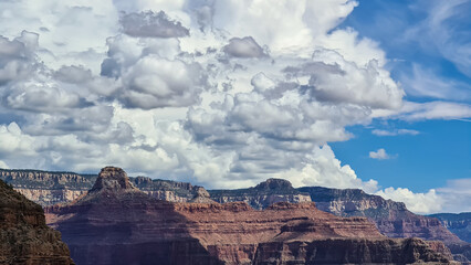 Scenic view on massive mesa cliff The Battleship seen from Bright Angel and Plateau Point hiking trail, South Rim of Grand Canyon National Park, Arizona, USA. Fluffy clouds wiht blue sky