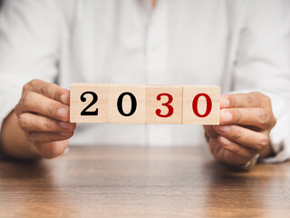 Countdown and Business Planning to 2030. Close-up of hand holding wooden cubes with the letters...