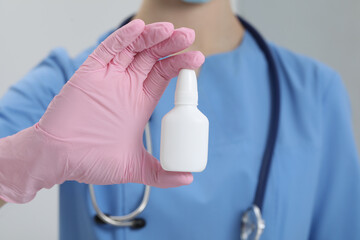 Doctor holding nasal spray on white background, closeup