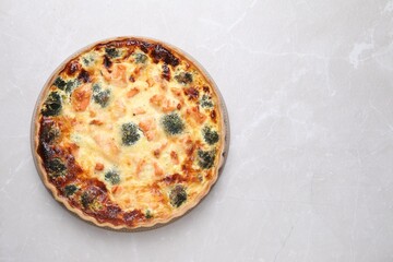 Delicious homemade quiche with salmon and broccoli on light gray marble table, top view. Space for text