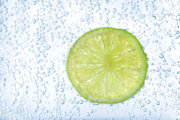 Juicy lime slice in soda water, closeup