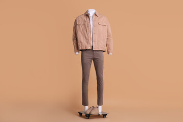 Fototapeta premium Male mannequin with sneakers dressed in white shirt, jacket and pants on beige background. Stylish outfit
