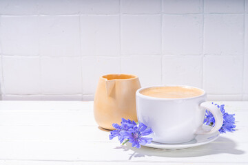 Chicory herbal coffee drink and blue flowers on white wooden table. Alternative vegan and keto diet coffee with chicory flowers and root powder 