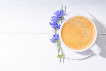 Chicory herbal coffee drink and blue flowers on white wooden table. Alternative vegan and keto diet coffee with chicory flowers and root powder 
