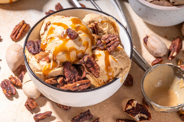 Pecan pie ice cream bowl. Traditional autumn spicy pecan caramel pie gelato taste, with rich caramel sauce and a lot of nuts, on kitchen table copy space