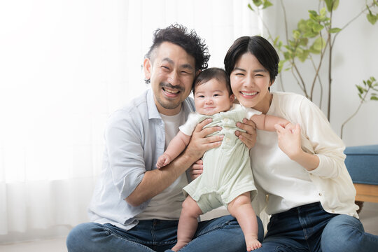 Cute smiling baby and friendly family in the living room looking at the camera