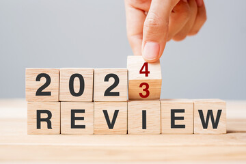 hand flipping block 2023 to 2024 REVIEW text on table. Resolution, idea, goal, motivation, reboot, business and New Year holiday concepts