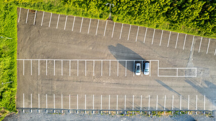 Aerial view of an almost empty parking lots with two parked cars during sunrise, casting long shadows. High quality photo