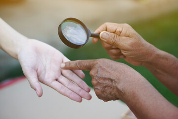 Closeup hand holds magnifying glass to inspect palm lines. Concept , palmistry, astrology....