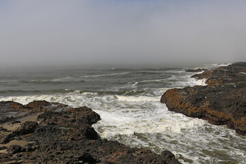 Fototapeta na wymiar Rocky coast in America. The waves crash against the rocks.