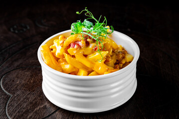 Salted French fries with bacon and cheese sause in white bowl on a wooden table