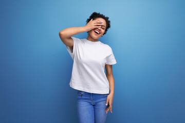 young brunette woman with afro hair in white t-shirt on studio background with copy space