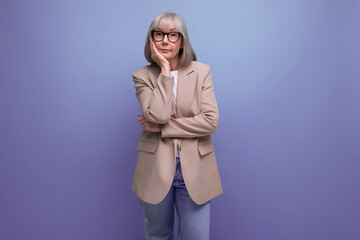 60s mature woman in business attire stands thoughtfully on a studio background with copy space