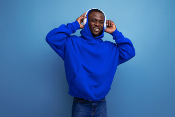 cool energetic dark-skinned american man with modern wireless headphones on the background with copy space