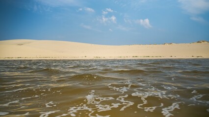 Surface of water with small waves on background of dunes in desert.