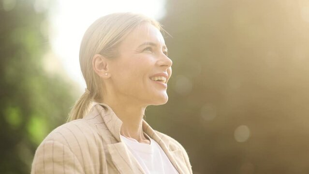 Portrait of confident mature blond woman looking ahead and exhaling fresh air taking deep breath and reducing stress after work at park Successful businesswoman resting for peaceful mind outdoors