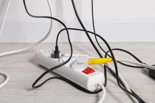 Power strip with electrical plugs on white floor indoors, closeup