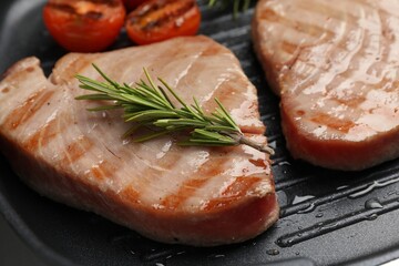 Delicious tuna steaks with rosemary in grill pan, closeup