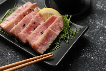 Pieces of delicious tuna steak served on black table, closeup