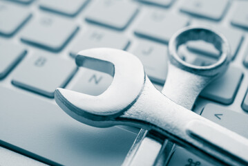 Wrench spanner on keyboard background. Customer online service center for troubleshooting quick...