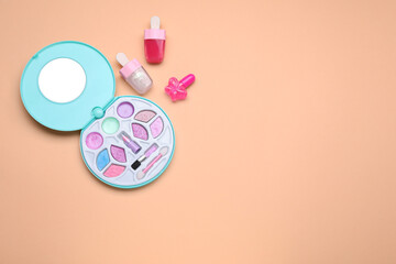 Children's makeup products and nail polish on pale orange background, flat lay. Space for text