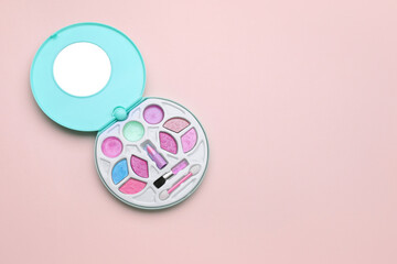 Decorative cosmetics for kids. Eye shadow palette with lipstick on pink background, top view. Space for text