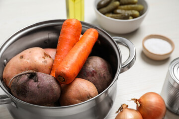 Fresh vegetables in pot on white table, closeup. Cooking vinaigrette salad