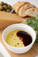 Bowl of organic balsamic vinegar with oil, basil and other products on table