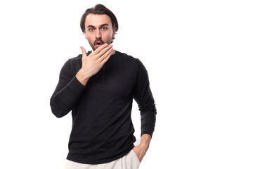portrait of surprised young handsome brunette man with hairstyle and beard dressed in black sweater isolated on white background with copy space