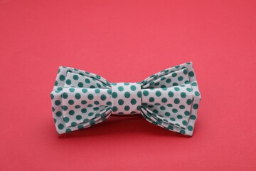 Stylish white bow tie with green polka dot pattern on red background