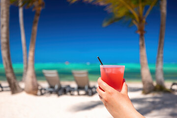Fototapeta na wymiar Exotic island beach with palm trees on the Caribbean Sea shore and summer refreshing cocktail pina colada
