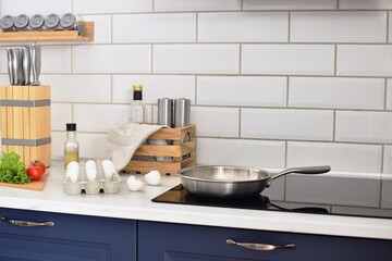 Cooking in a steel pan on an induction hob.  A frying pan on the stove, eggs, tomatoes, herbs on...