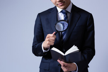 虫眼鏡で手帳を見る男性ビジネスマン