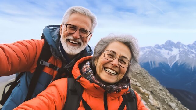 Happy smile elderly couple of hikers in the ascent to the summit take a selfie phone on the snow highlands landscape around
