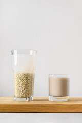 Vegan raw green buckwheat milk on white background. Cooking plant based alternative milk replacer. Vertical format. Copy space.