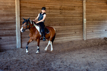 Beautiful young rider with green eyes galloping during her riding lesson