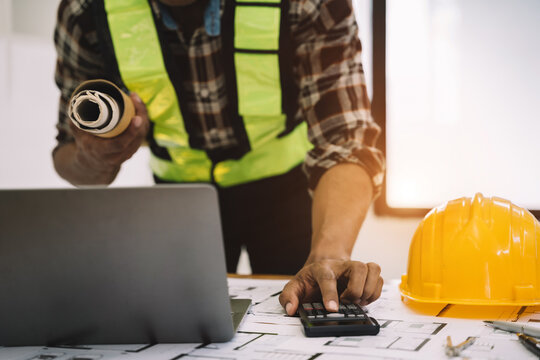 civil engineer or architect business useing calculator about calculate the cost with for working building plan design project in office.