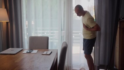 Trouble breathing, chest pain. Close up man having difficulty breathing pain heart, touches chest with hand sitting on couch at home. Heart attack, thoracic osteochondrosis, panic attack concept