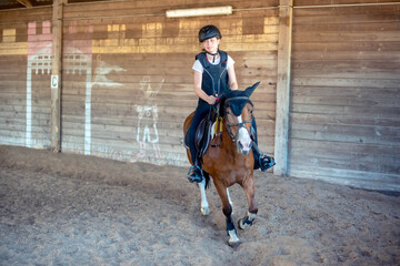 Beautiful young rider with green eyes galloping during her riding lesson
