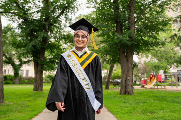 High school woman who wears a hijab a robe and graduation mortar board and tassel.