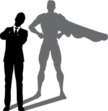 A superhero business man revealed by his shadow silhouette as a super hero in a cape